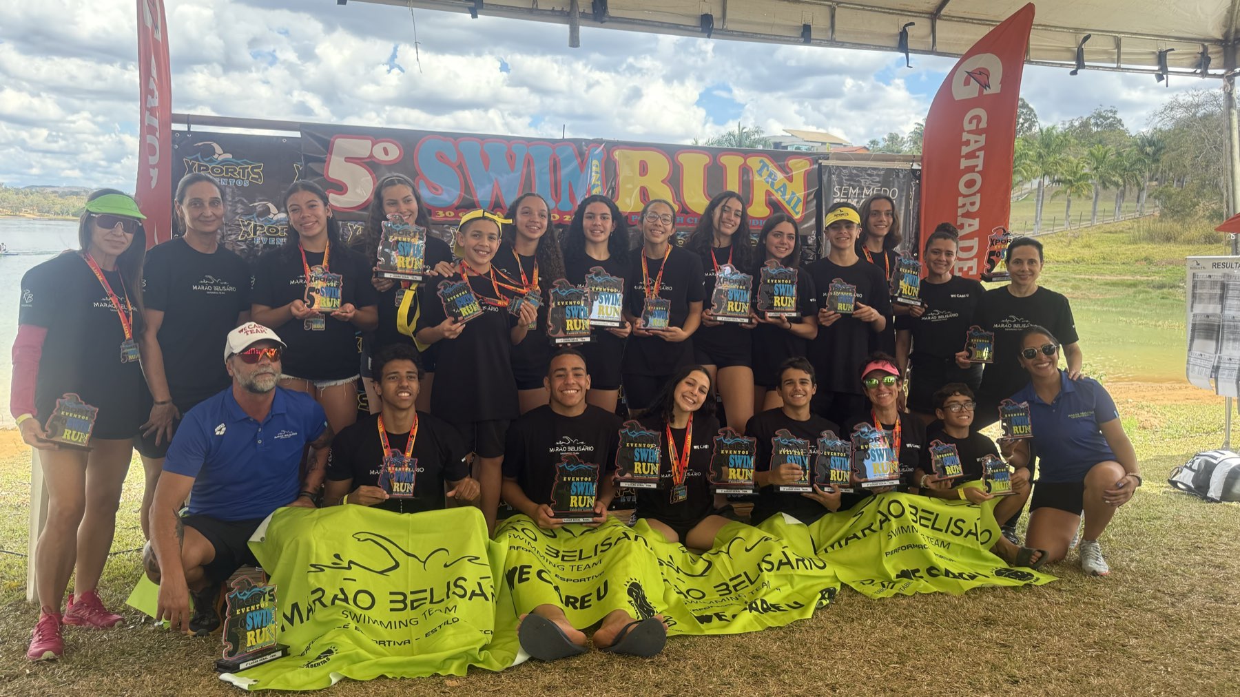 Equipe com troféus após prova de swim and run à beira do lago