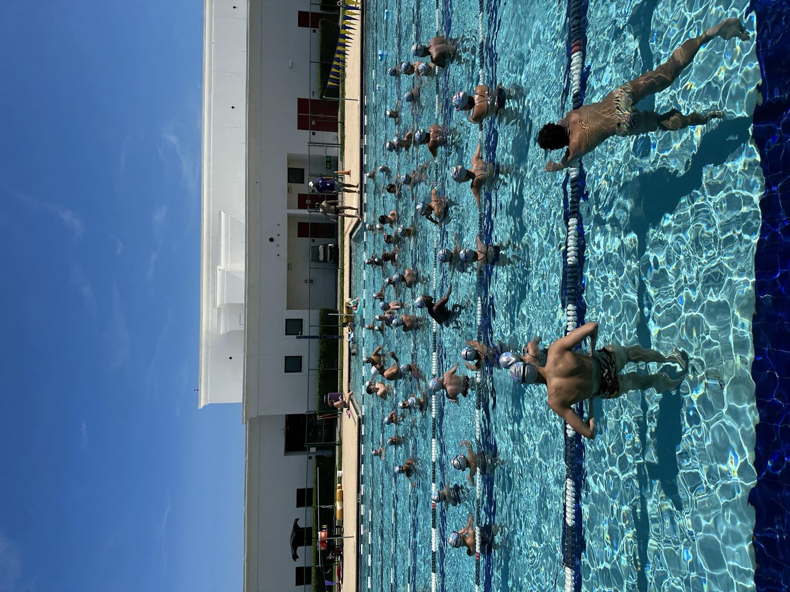 Turma grande em exercício na piscina externa em dia de sol